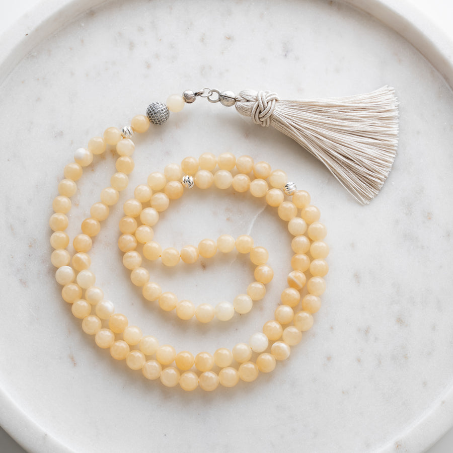 Calcite tasbih (misbaha) with 99 natural calcite beads, silver separators and a cream tassel on white marble
