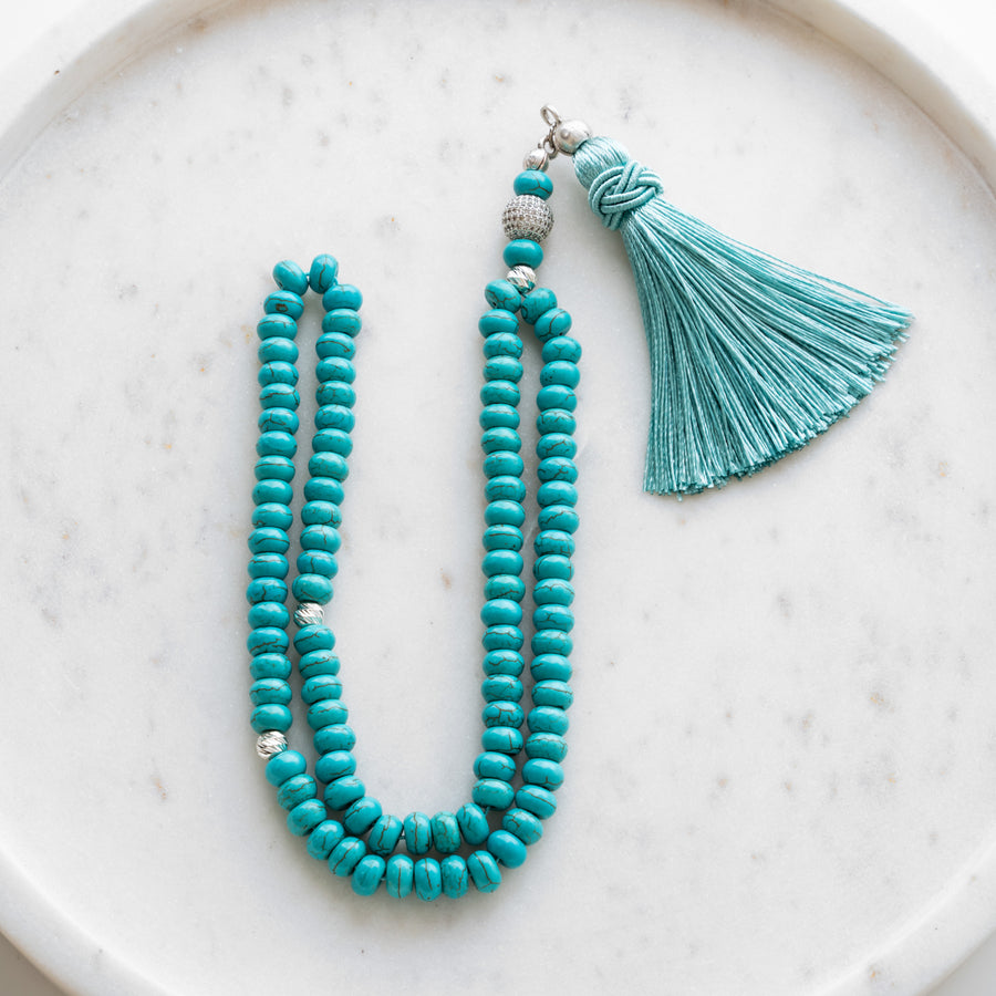 Turquoise tasbih (misbaha) with 99 flat turquoise beads, silver separators and a turquoise tassel on white marble